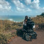 Tori sitting in her wheelchair and looking out at the ocean at a lookout point on the Road to Hana