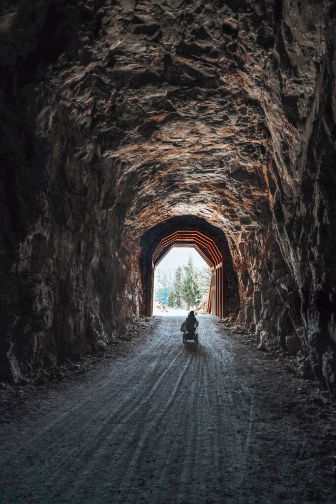 Tori driving her wheelchair through a cave at the Myra Canyon Trestles