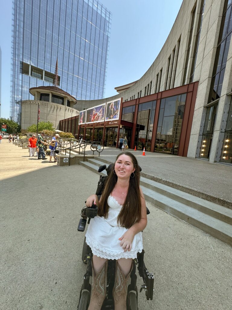 Tori Hunter, wheelchair accessible travel blogger, sitting in her wheelchair outside of the Country Music Hall of Fame in Nashville Tennessee