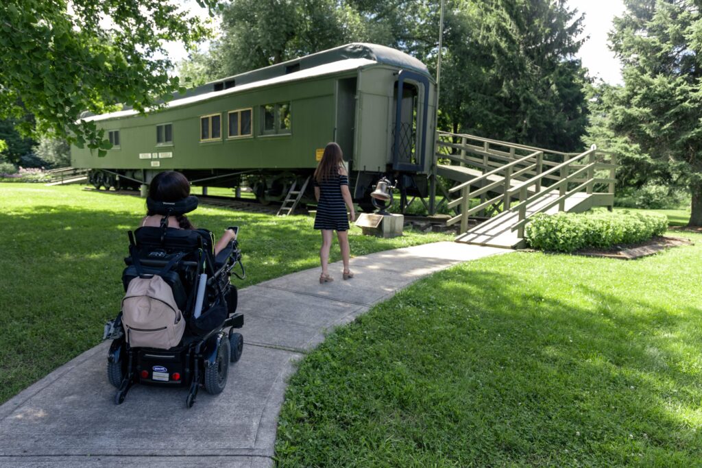 Tori using the ramp to enter the School on Wheels Museum in Central Huron, Ontario. The accessible entrance makes the museum wheelchair friendly for visitors.