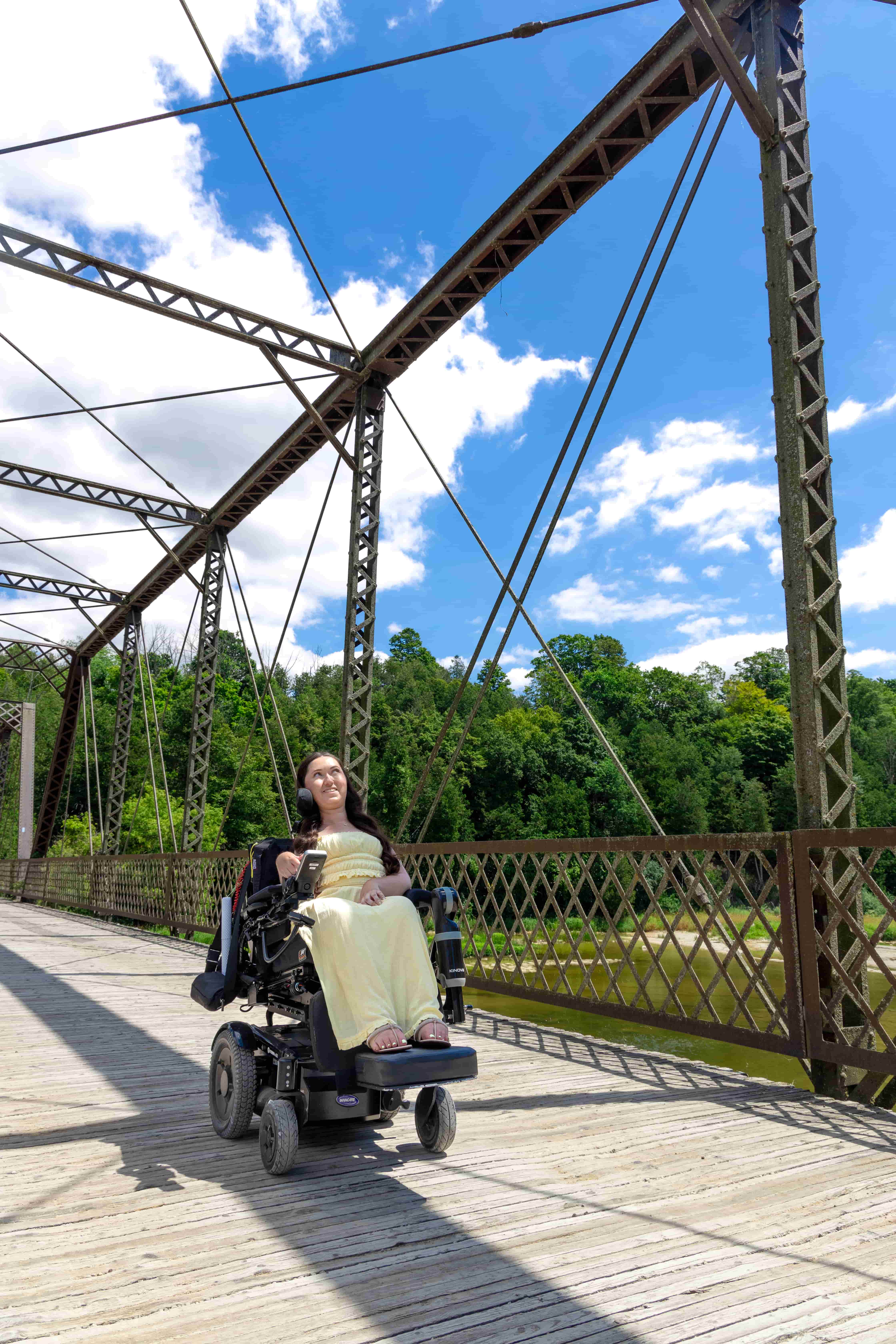 Tori, a wheelchair accessible travel blogger, crossing Balls Bridge in her power wheelchair in Central Huron, Ontario. The historic bridge offers a scenic and accessible outing.