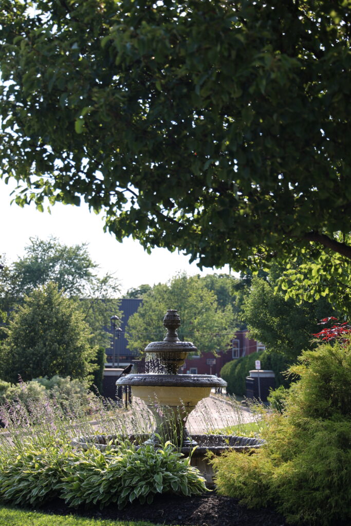 A stone fountain surrounded by hostas and flowering salvia in the garden courtyard at The Bruce Hotel in Stratford, Ontario