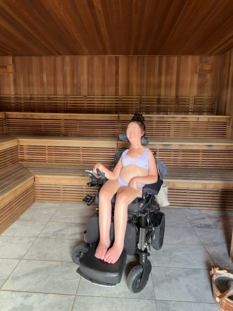 Tori Hunter, a wheelchair user and disabled travel blogger, relaxing in her power wheelchair inside the sauna at Wave Nordic Spa in Mount Elgin, Oxford County, Ontario