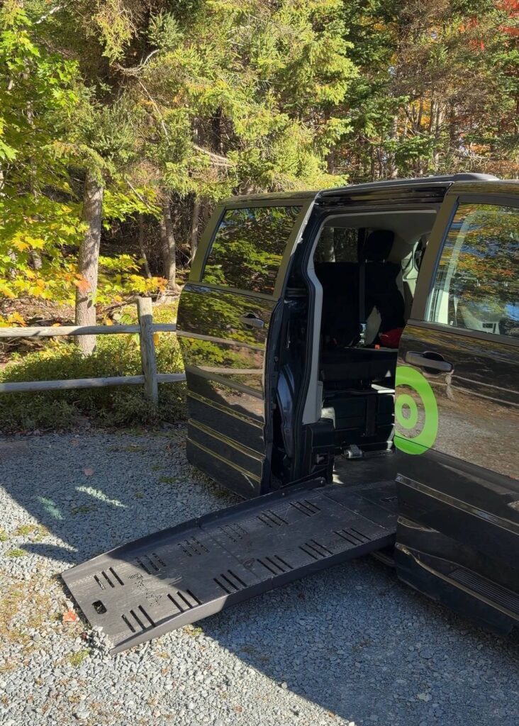 Communauto's wheelchair accessible rental van in Halifax with the side door open and its automated side-entry ramp lowered onto a gravel parking lot in Nova Scotia