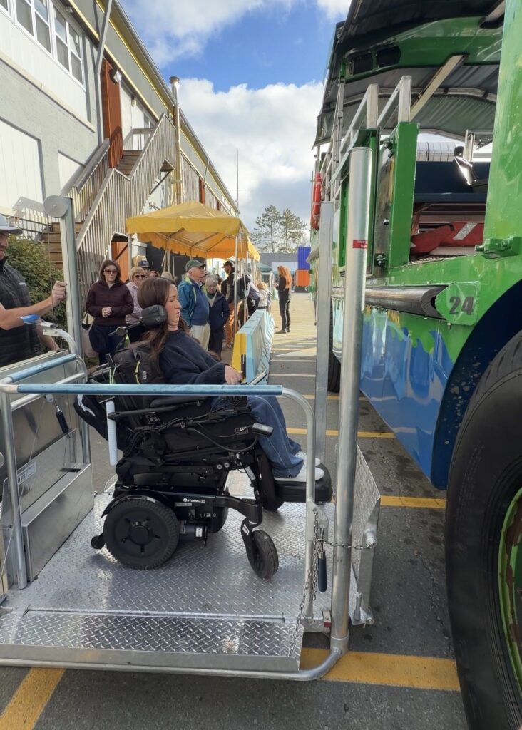 Tori Hunter, a wheelchair user and disabled travel blogger, being raised in her power wheelchair on the wheelchair lift of the amphibious Harbour Hopper tour vehicle in Halifax, Nova Scotia