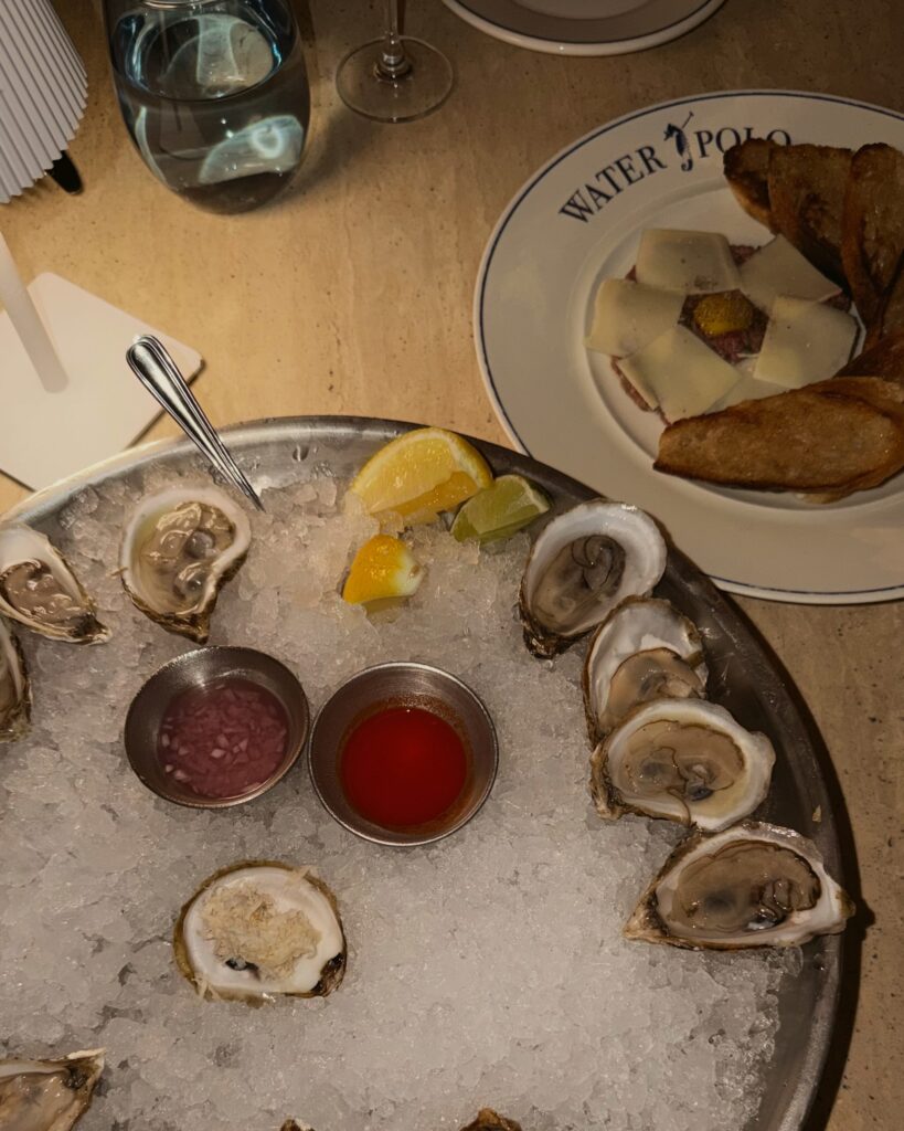 Platter of fresh oysters on ice with mignonette and hot sauce next to a tartare starter at Waterpolo, a wheelchair accessible restaurant on the Halifax waterfront in Nova Scotia